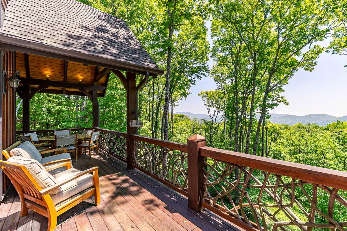 An inviting wooden deck with comfortable seating, overlooking serene mountain scenery and trees. The setting is perfect for enjoying coffee at sunrise, listening to concerts from afar, or sharing peaceful moments with loved ones (and pets).
